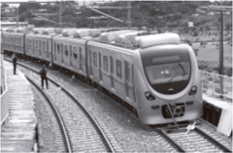 Fotografia em preto e branco exibindo uma composição moderna de trem metropolitano (ou metrô) trafegando sobre trilhos.