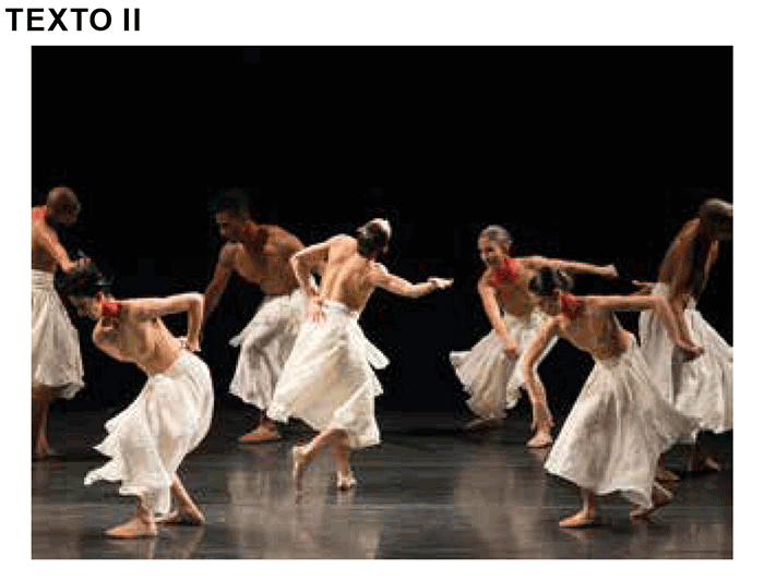 Fotografia do espetáculo Gira, do Grupo Corpo. Bailarinos aparecem com o torso nu e saias brancas longas, executando movimentos que remetem à giras de religiões de matriz africana, em um cenário minimalista e iluminação dramática.