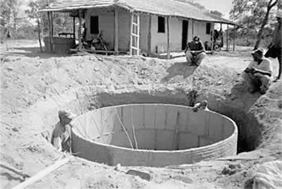Foto da construção de uma cisterna cilíndrica de alvenaria em uma área rural.